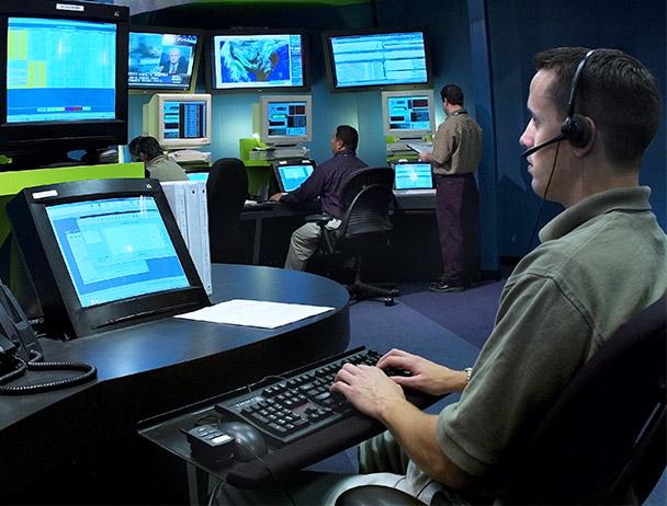 三名Viasat网络运营员工在电脑和电视显示器上监控数据